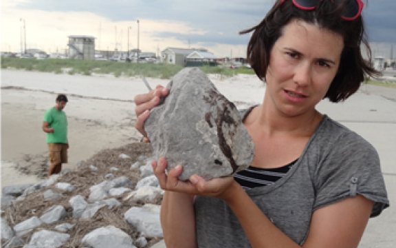 Onderzoeker Helen White houdt een rotssteen vast met olieafzetting op een strand aan de Golf van Mexico