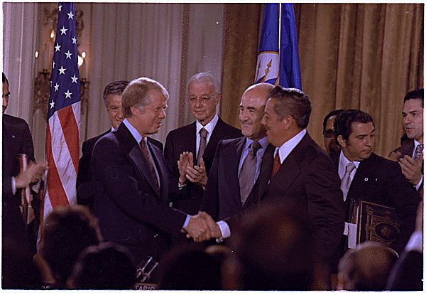 President Jimmy Carter schudt de hand van Panamees regeringsleider Omar Torrijos na het ondertekenen van een nieuw verdrag over het Panamakanaal in 1977