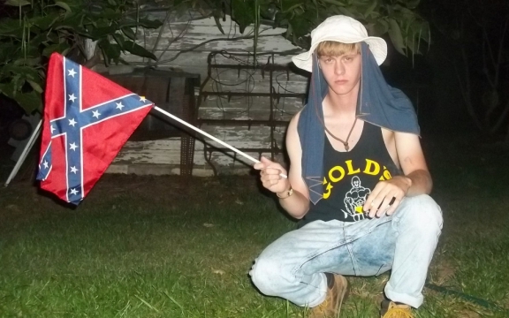 Een eigen foto van Dylann Roof op zijn website, kort voor hij zijn moordende aanslag pleegde, met een vlag van de Geconfedereerde Staten van Amerika
