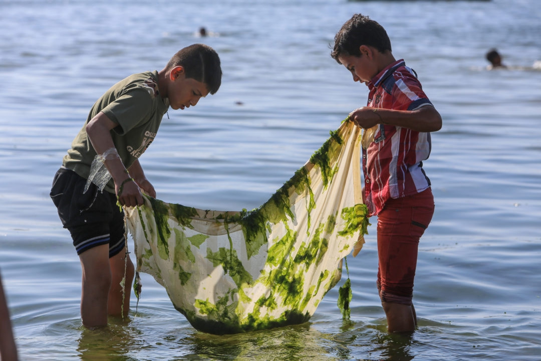 Twee Palestijnse jongens proberen wat vis te vangen aan de kust van Gaza