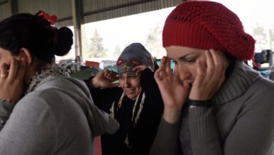 Syrische vluchtelingen in Idomeni (aan de grens met Macedonië) stoppen hun oren af voor overvliegende jets van de Griekse luchtmacht. Deze geluiden kennen ze al.